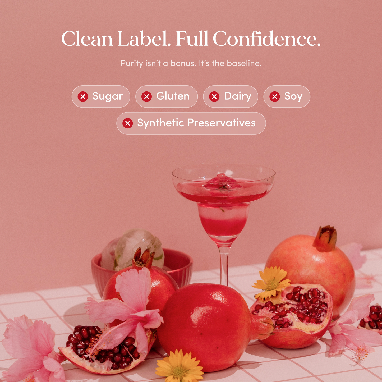 Pink drink in a glass with pomegranates and flowers on a pink background, promoting clean label and confidence.
